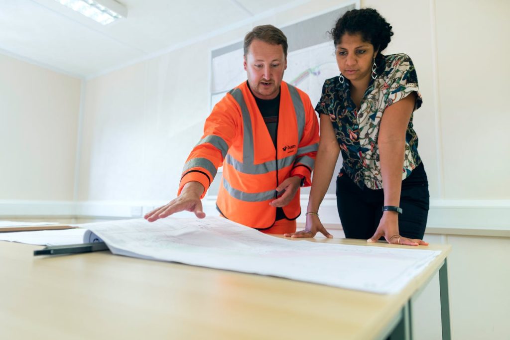 Overcoming Challenges Lessons Every Entrepreneur Must Learn Two engineers reviewing blueprints in an office, discussing project details.