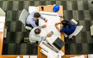 Top view of a team working on construction plans in an office setting. Atlas Prime Building Contracting Dubai UAE